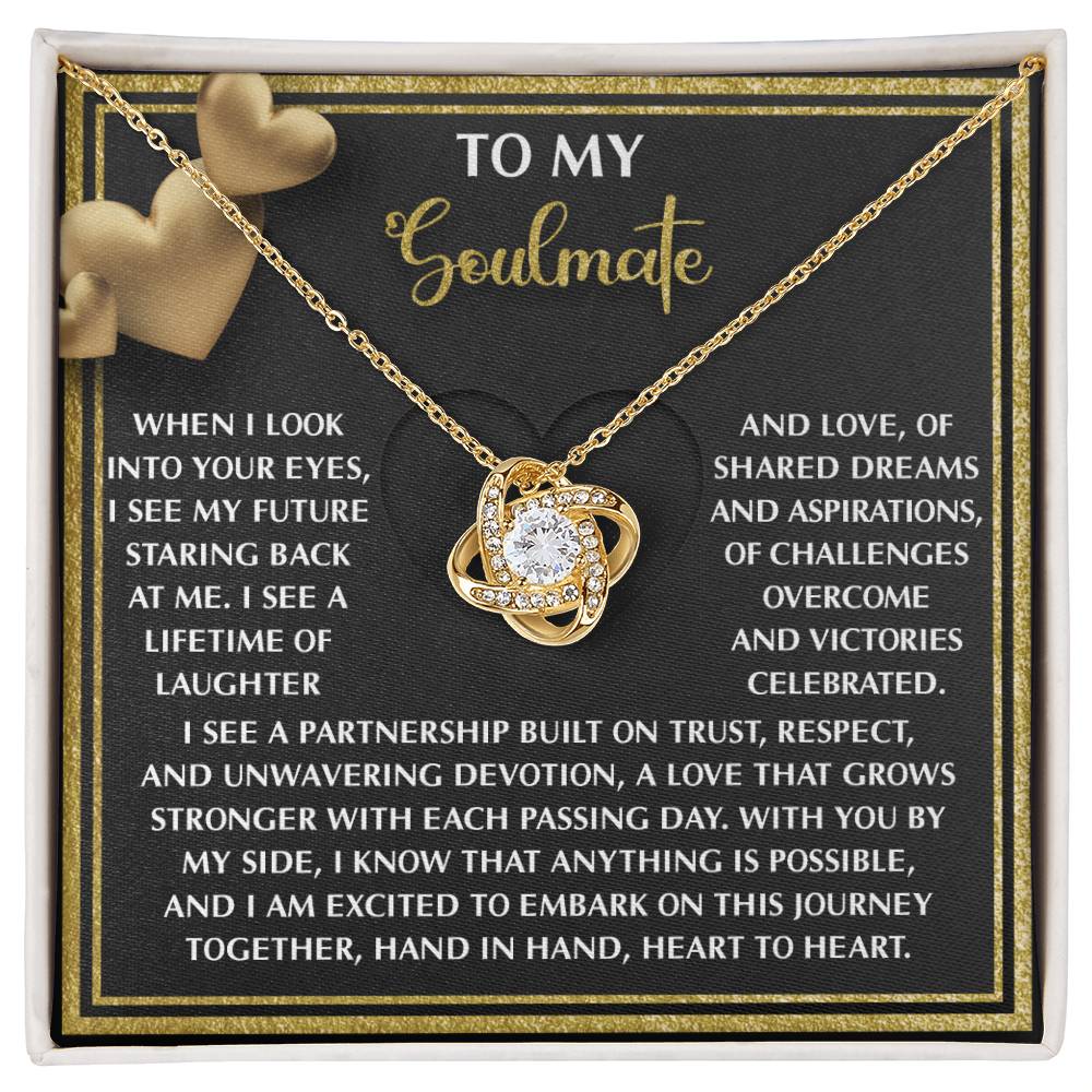 The Soulmate-Heart To Heart - Love Knot Necklace features a circular pendant in a box. The lid displays "To My Soulmate" with a heartfelt message about love, dreams, and partnership alongside gold heart graphics. This personalized gift sparkles with cubic zirconia accents.