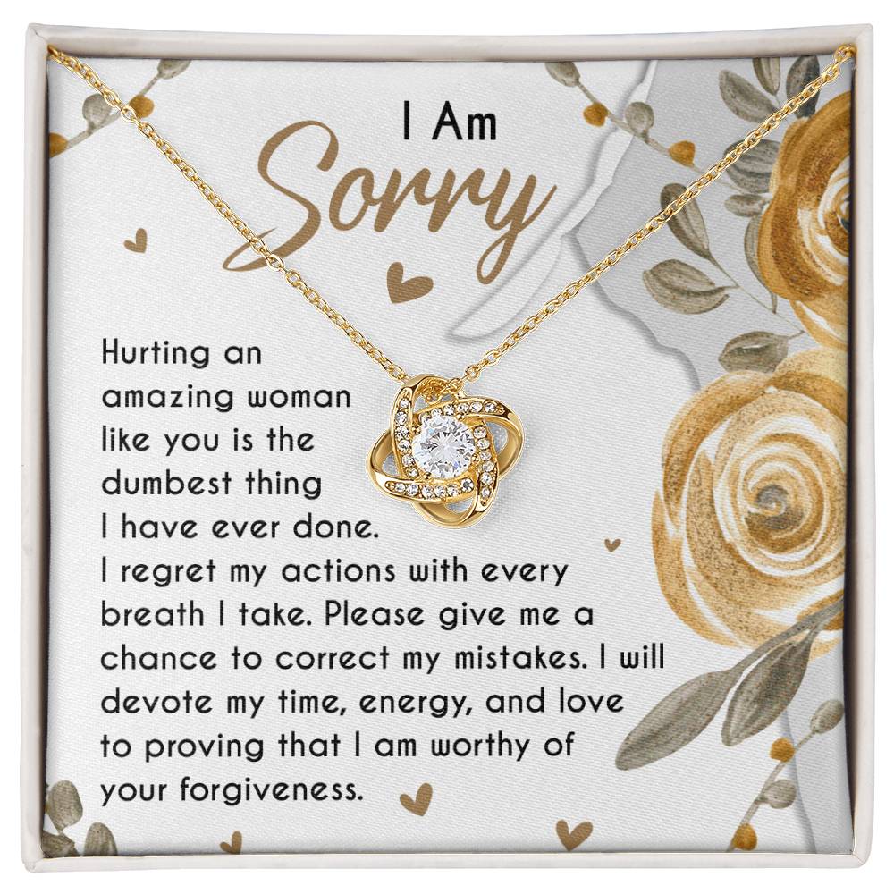 The Sorry-Amazing Woman - Love Knot Necklace, adorned with cubic zirconia crystals, rests in a jewelry box on a heartfelt note that reads, "I Am Sorry. Hurting an amazing woman like you is the dumbest thing I have ever done..." along with more apologetic text.