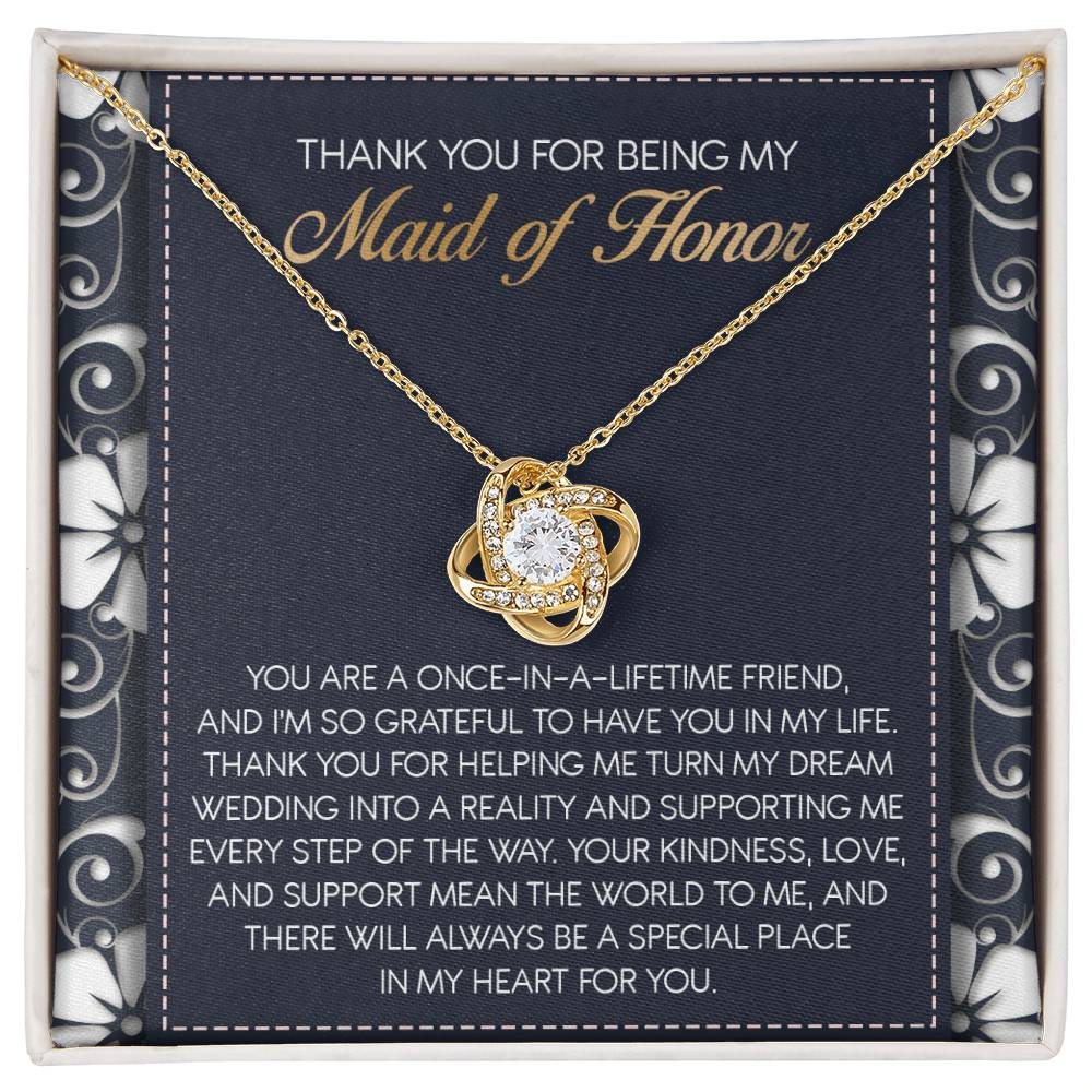 The "To Maid of Honor, World To Me - Love Knot Necklace" features a heart-shaped pendant adorned with Cubic Zirconia Crystals. It comes beautifully packaged in a box that includes an inscribed thank-you note, expressing heartfelt gratitude to the Maid of Honor, making it a perfect personalized gift.