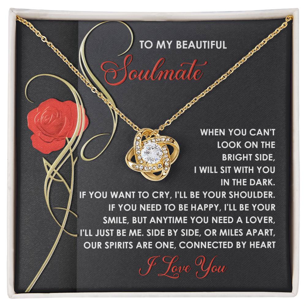 The Soulmate-Be Me Love Knot Necklace, with a gold finish and cubic zirconia-adorned pendant, is showcased against a red rose backdrop with the message "To My Beautiful Soulmate.