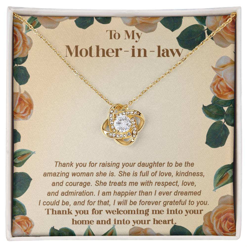 The "To Mother-in-law, Grateful To You - Love Knot Necklace" is a gold necklace featuring a diamond pendant displayed against a floral backdrop adorned with cubic zirconia crystals. It comes with a heartfelt message expressing gratitude to your mother-in-law, making it a truly personalized gift.