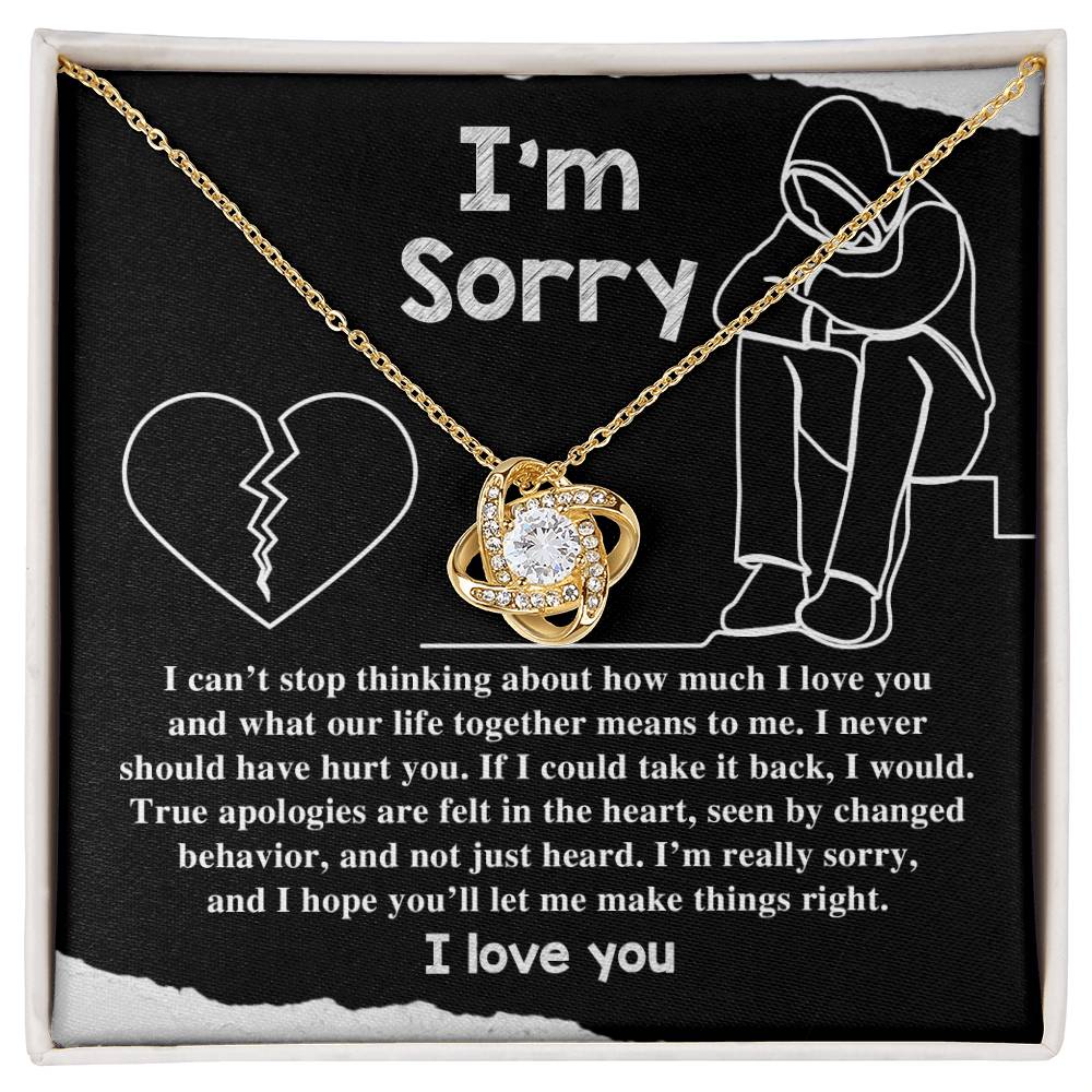 The "Sorry-Not Just Heard - Love Knot Necklace" features an apology message on a black background. The heartfelt text expresses regret and a promise to change, accompanied by illustrations of a heart and a person sitting with their head down. Cubic zirconia crystals add a touch of elegance, with "I love you" written at the bottom.