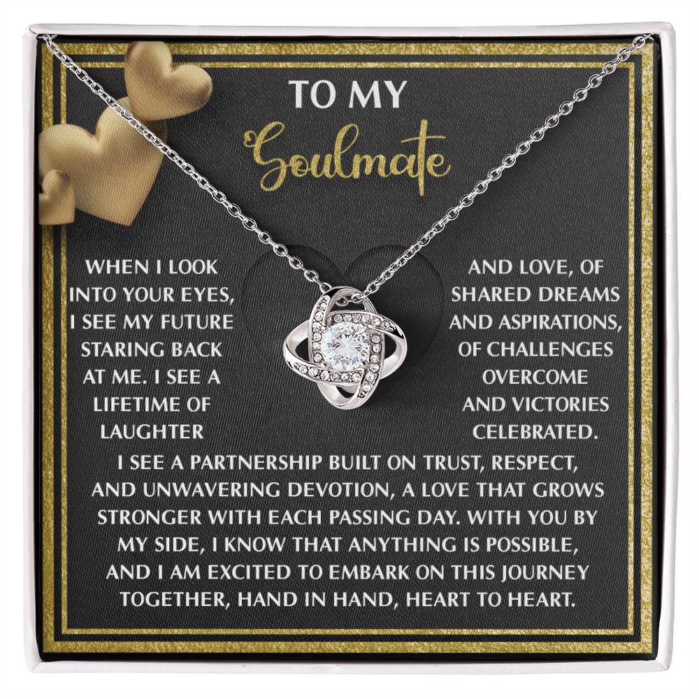 The Soulmate-Heart To Heart - Love Knot Necklace boasts an intertwined heart design with sparkling cubic zirconia crystals, displayed on a "To My Soulmate" card featuring a touching love message, and is available in white or yellow gold finishes.