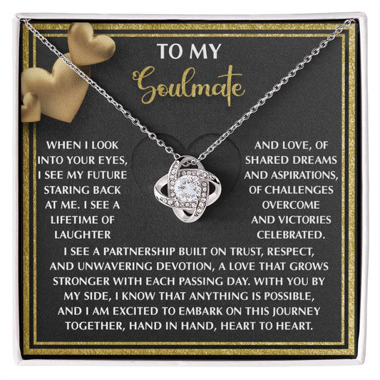 The Soulmate-Heart To Heart - Love Knot Necklace boasts an intertwined heart design with sparkling cubic zirconia crystals, displayed on a "To My Soulmate" card featuring a touching love message, and is available in white or yellow gold finishes.