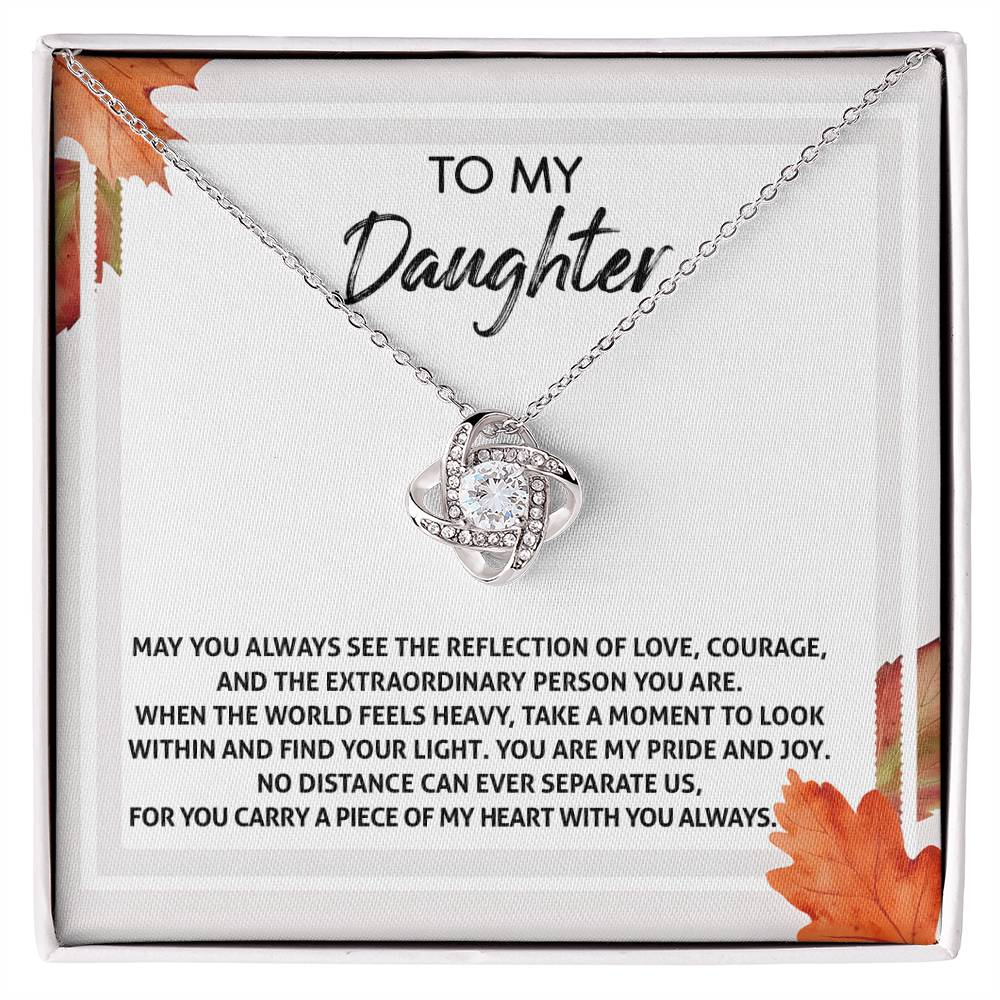 Introducing the "Daughter-Find Your Light - Love Knot Necklace," featuring an intertwined design on a chain, adorned with cubic zirconia crystals and available in either a white gold or yellow gold finish. This beautiful necklace is presented on a card with an inspirational message for your daughter, all encased in a box decorated with autumn-themed accents.