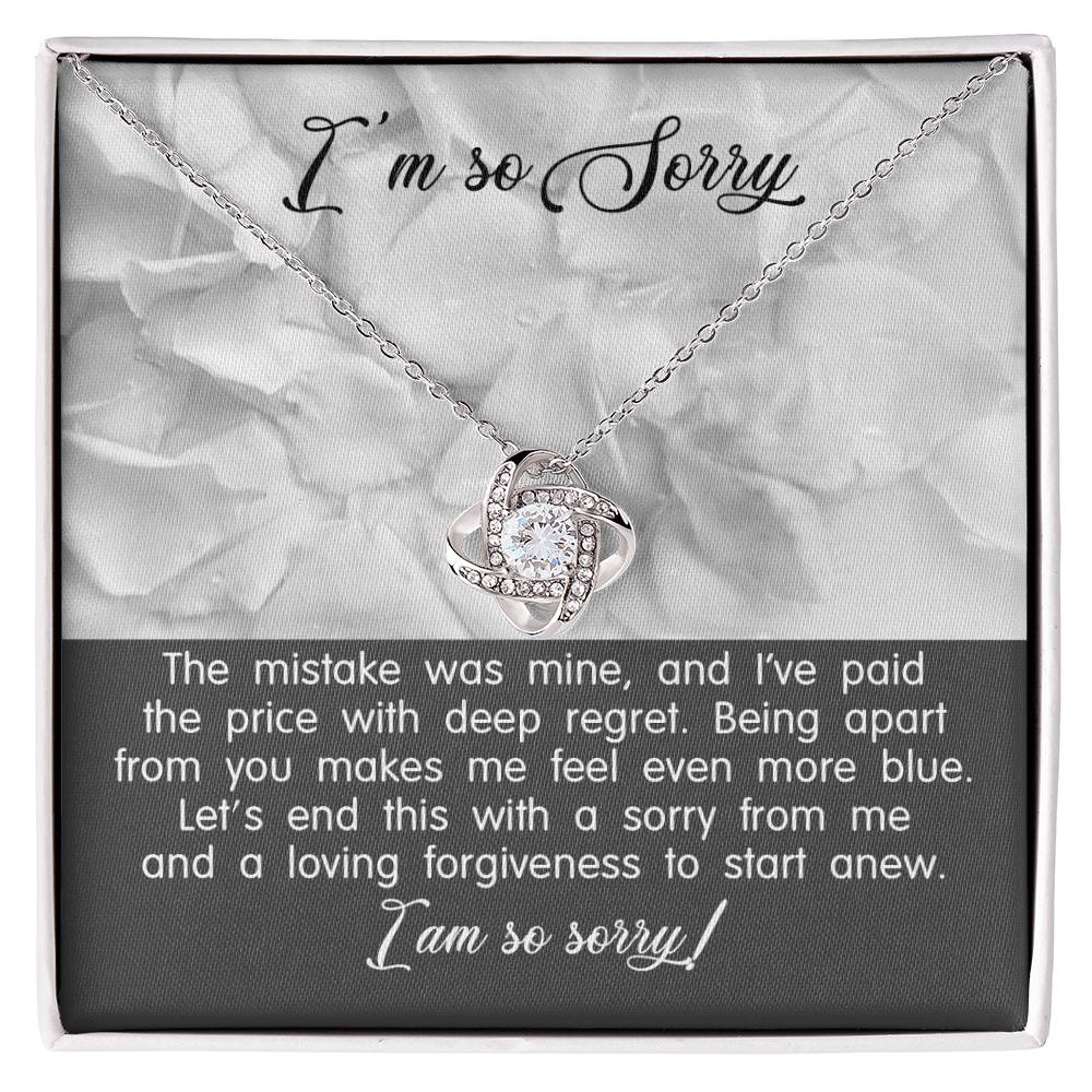 A Sorry-With Deep Regret - Love Knot Necklace with a white gold finish and a pendant on a card that says "I'm so Sorry." The card contains an apology message expressing regret and a plea for forgiveness.