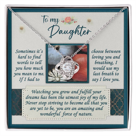 The Daughter-Force Of Nature - Love Knot Necklace, featuring a gold finish and embellished with cubic zirconia crystals, is beautifully presented on a card with a heartfelt message dedicated to a daughter, expressing love, pride, and encouraging her to continue striving for her dreams.