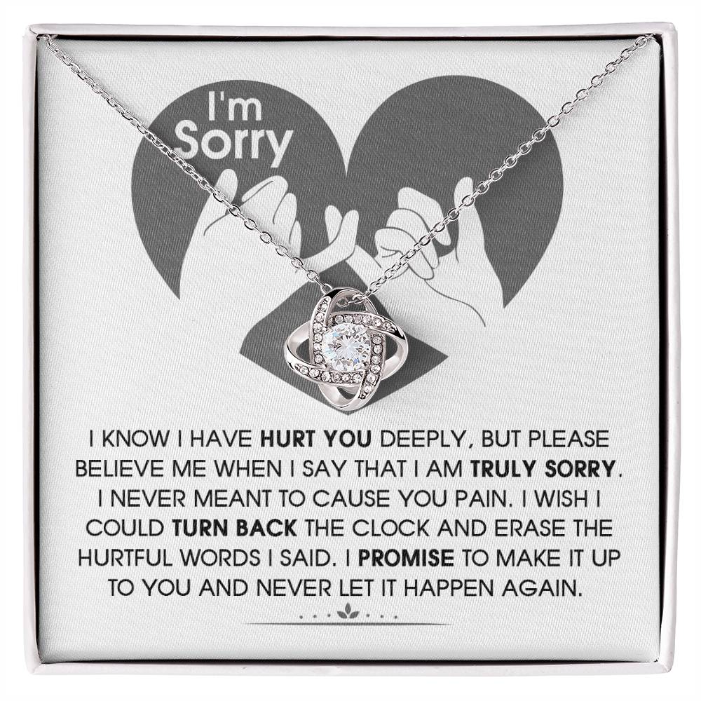 The Sorry-Hurtful Words Love Knot Necklace is displayed on a card featuring an illustration of a heart and hands. The card conveys an apology message that expresses deep regret and a promise to make amends. This personalized gift is adorned with cubic zirconia, symbolizing the depth of sincerity and commitment.