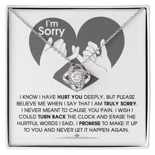 The Sorry-Hurtful Words Love Knot Necklace is displayed on a card featuring an illustration of a heart and hands. The card conveys an apology message that expresses deep regret and a promise to make amends. This personalized gift is adorned with cubic zirconia, symbolizing the depth of sincerity and commitment.