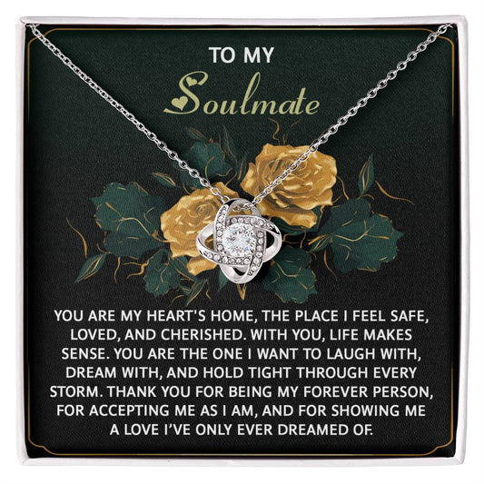 The Soulmate-Forever Person - Love Knot Necklace showcases an intertwined knot design embellished with cubic zirconia crystals, elegantly packaged in a box featuring a floral background and sentimental message, creating the ideal personalized gift.