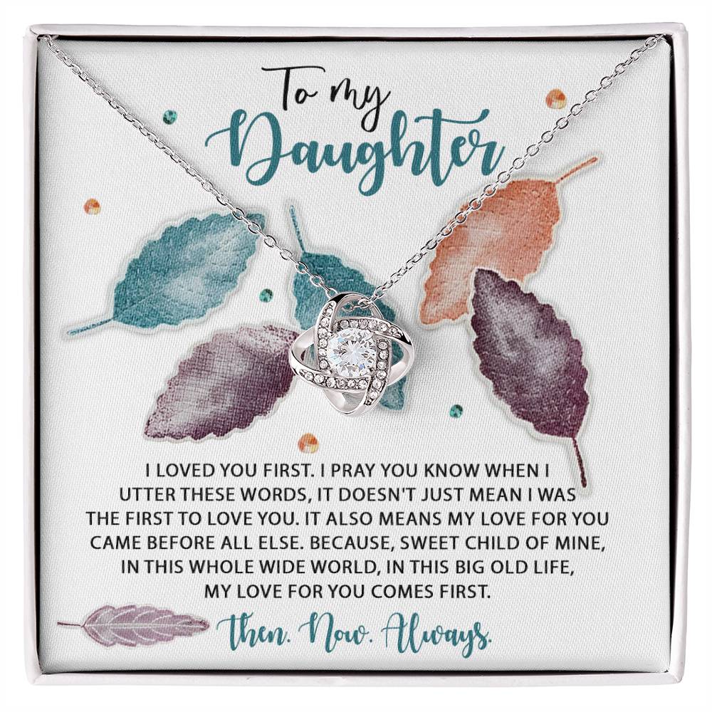 The Daughter-Pray You Know - Love Knot Necklace, adorned with sparkling Cubic Zirconia Crystals and surrounded by illustrations of leaves, is displayed on a card that reads: “To my Daughter. I loved you first… my love for you comes first. Then. Now. Always.” This Gold Finish necklace with its elegant heart-shaped pendant is a symbol of timeless affection.