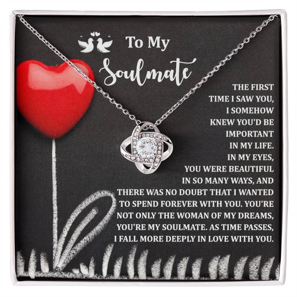 The Soulmate-Forever With You Love Knot Necklace, adorned with sparkling cubic zirconia crystals, is presented on a card with a red heart illustration and a message about love and soulmates—an ideal personalized gift.
