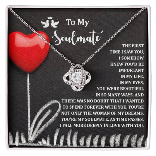 The Soulmate-Forever With You Love Knot Necklace, adorned with sparkling cubic zirconia crystals, is presented on a card with a red heart illustration and a message about love and soulmates—an ideal personalized gift.