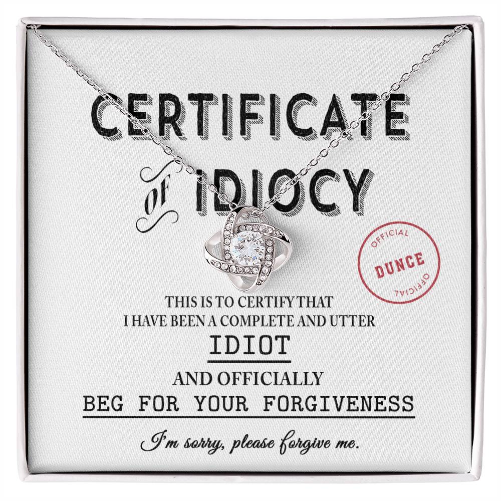 The Sorry-Certificate Of Idiocy - Love Knot Necklace rests on a card adorned with an apology message and an "Officially a Dunce" stamp.