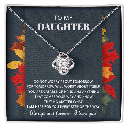 The Daughter-Comes Your Way - Love Knot Necklace showcases an intricate design and is elegantly presented in a gift box. It features a heartfelt message for a daughter, emphasizing love, support, and resilience. Adorned with cubic zirconia crystals, the necklace comes with a background featuring autumn leaves.