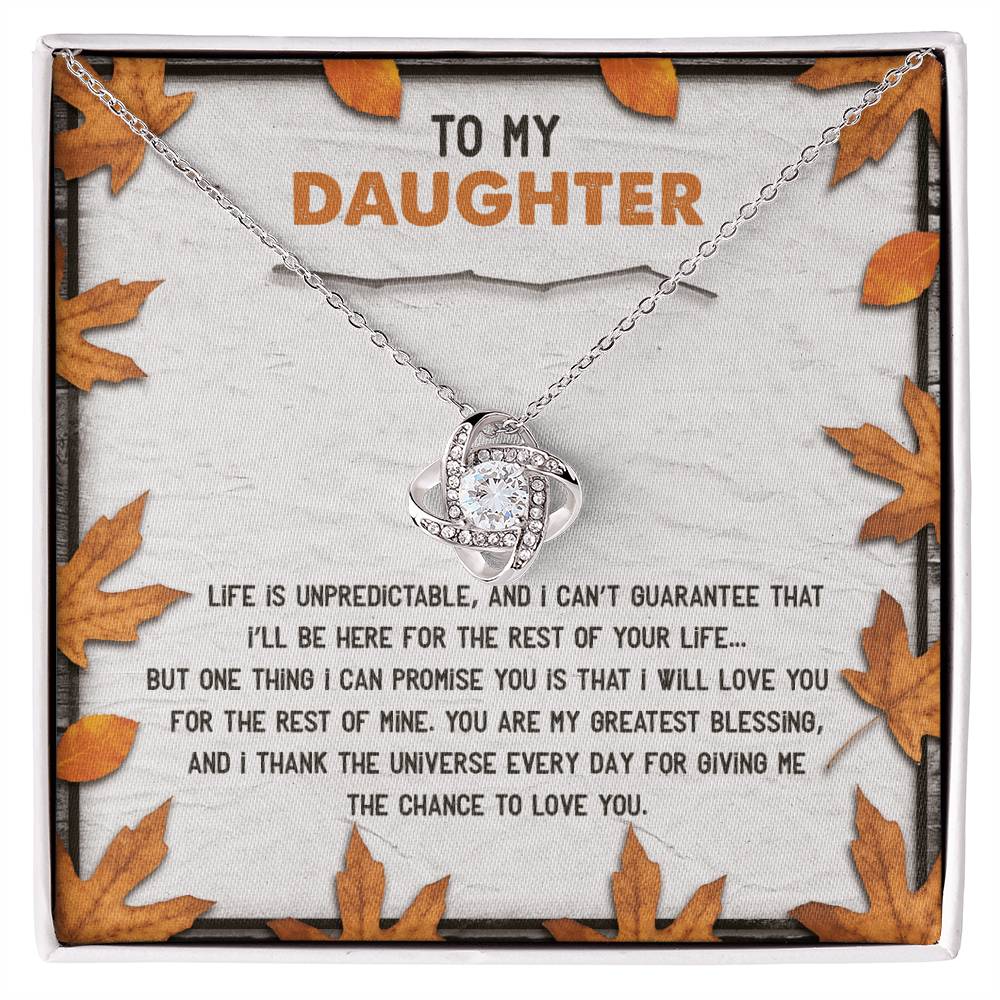 The Daughter-My Greatest Blessing - Love Knot Necklace, featuring an interlocking design and adorned with cubic zirconia crystals, is beautifully presented on a message card decorated with autumn leaves. The card reads, "To my daughter, Life is unpredictable...thank the universe every day for giving me the chance to love you.
