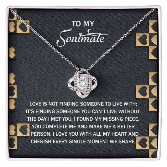 The Soulmate-Missing Piece Love Knot Necklace is a silver heart with an entwined design and gold finish, presented on a black card with gold heart accents and a sentimental message about love and soulmates celebrating their timeless bond.
