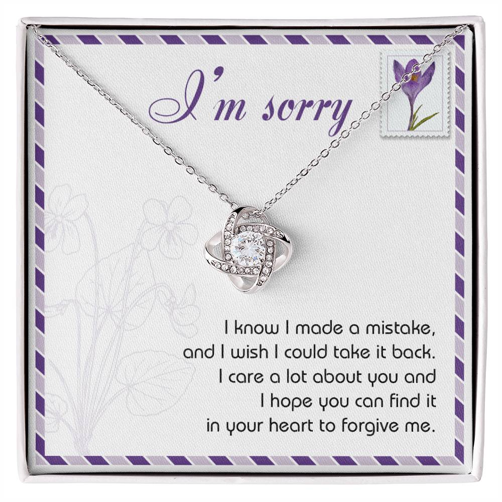 The "Sorry, Take It Back - Love Knot Necklace," featuring a silver pendant embellished with shimmering cubic zirconia crystals, is presented on a sympathy card that reads, "I'm sorry. I know I made a mistake, and I wish I could take it back. I care a lot about you and hope you can forgive me.