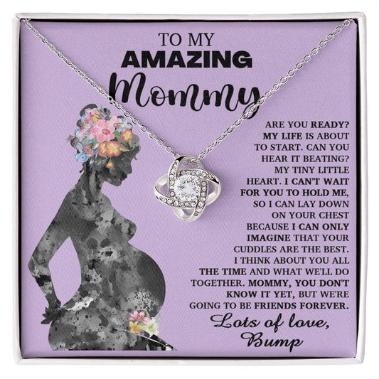 The "To Mom To Be, Tiny Little Heart - Love Knot Necklace" features an intertwined pendant and is beautifully presented on a card showcasing a silhouette of a pregnant woman, accompanied by a heartfelt message from "Bump" to "Mommy." This elegant necklace is adorned with premium cubic zirconia crystals, symbolizing their unbreakable bond.
