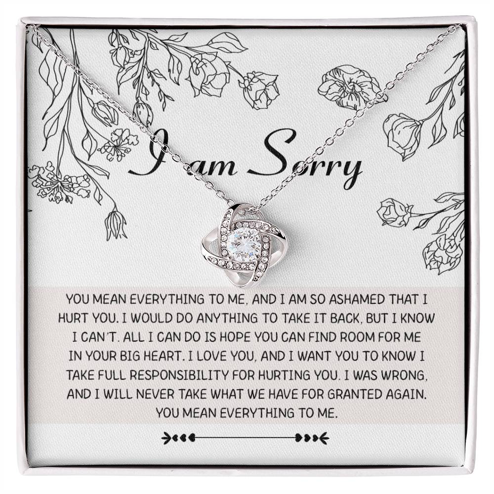 Introducing the "Sorry-Your Big Heart - Love Knot Necklace": This exquisite white gold necklace showcases an elegant intertwined heart design, adorned with shimmering cubic zirconia crystals. It comes complete with a heartfelt card that reads, "I am Sorry," followed by an apologetic message. The entire set is beautifully presented in a floral-printed box.