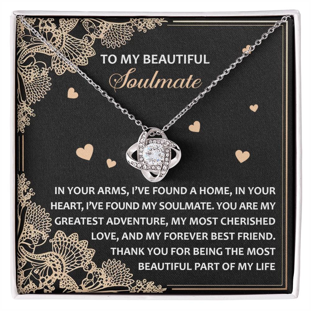 The Soulmate-Beautiful Part Love Knot Necklace features an interlocking heart pendant with a white gold finish, elegantly presented on a black card with a heartfelt message about love. Embedded with cubic zirconia crystals, it symbolizes timeless bonds and eternal affection.