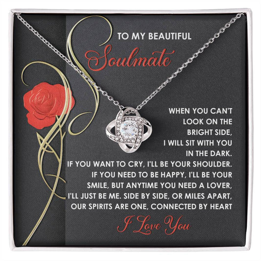 The Soulmate-Be Me Love Knot Necklace features an intricate pendant with sparkling cubic zirconia, presented against a box showcasing a romantic message, red rose illustration, and decorative text for your soulmate. Available in a luxurious gold finish, it symbolizes everlasting love.