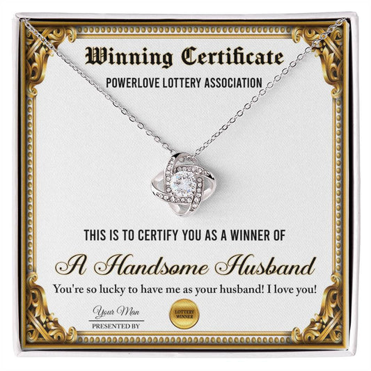 A "To Wife, Winning Certificate - Love Knot Necklace" is displayed against a certificate text background reading, "Winning Certificate - Powerlove Lottery Association - A Handsome Husband," featuring shimmering cubic zirconia crystals and an elegant gold finish.