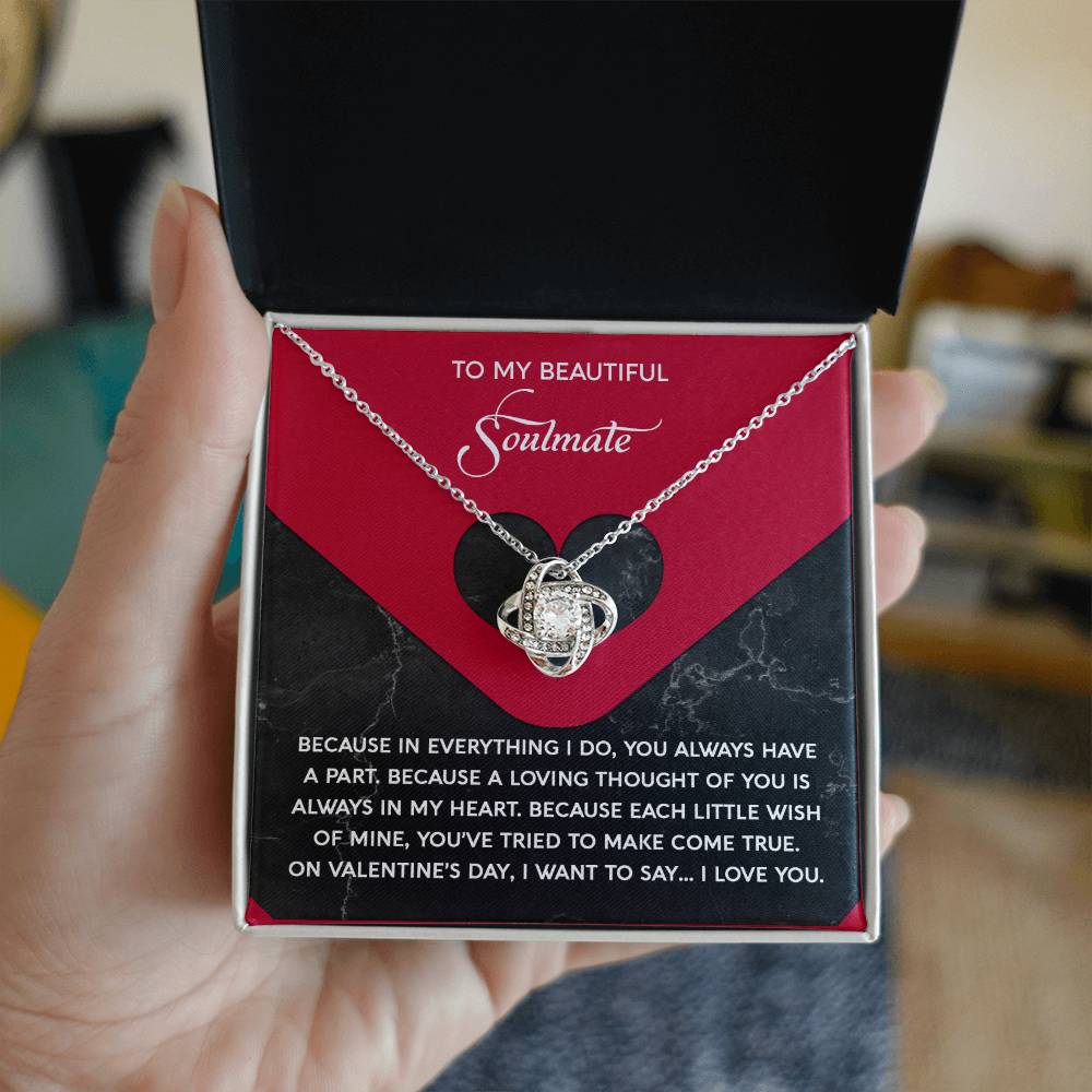 A hand holds a box with the dazzling Soulmate-Loving Thought - Love Knot Necklace, featuring interwoven hearts and cubic zirconia crystals. The inner lid reads, "To My Beautiful Soulmate," followed by a romantic message—a truly personalized gift for your beloved.
