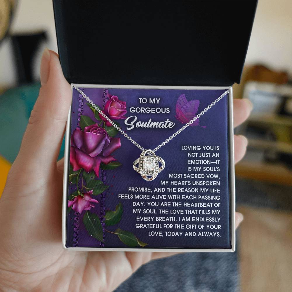 The Soulmate-Unspoken Promise - Love Knot Necklace, featuring sparkling cubic zirconia crystals, is beautifully packaged in a gift box. Inside, a card reads "To My Gorgeous Soulmate," with a romantic message and purple rose illustrations, creating the perfect personalized gift.
