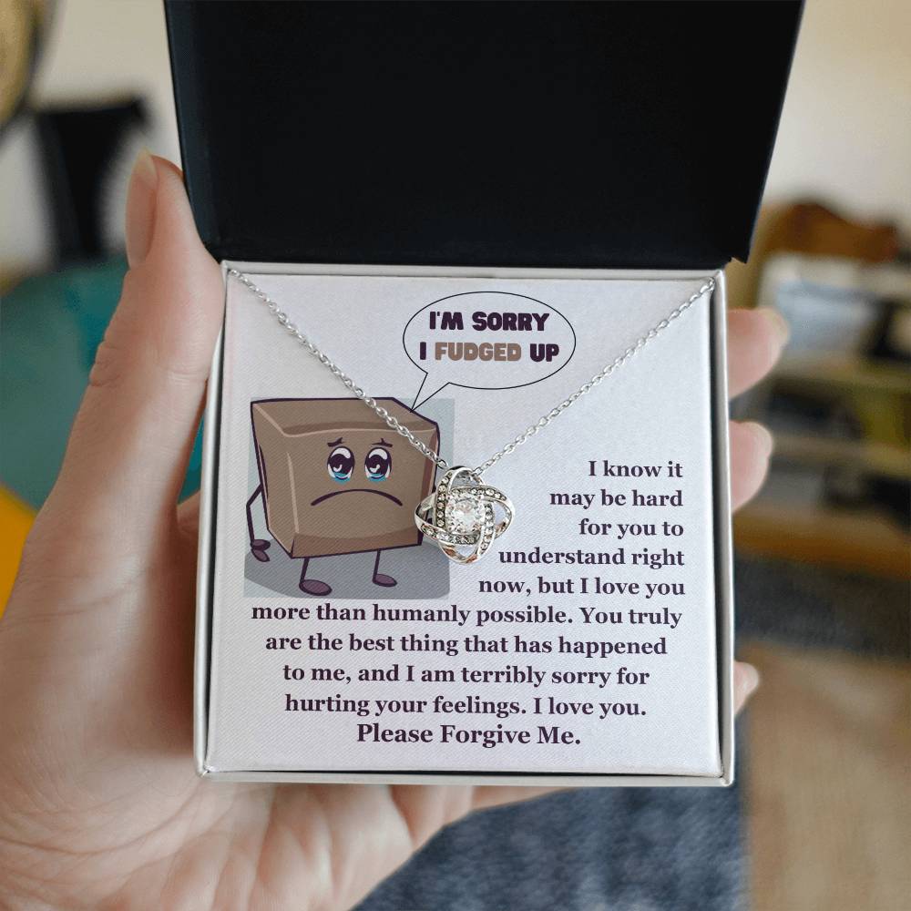 The "Sorry-The Best Thing" Love Knot Necklace, crafted in 14k white gold and adorned with shimmering cubic zirconia crystals, is presented elegantly in a box. The cover showcases an apologetic cartoon, expressing deep regret and asking for forgiveness.