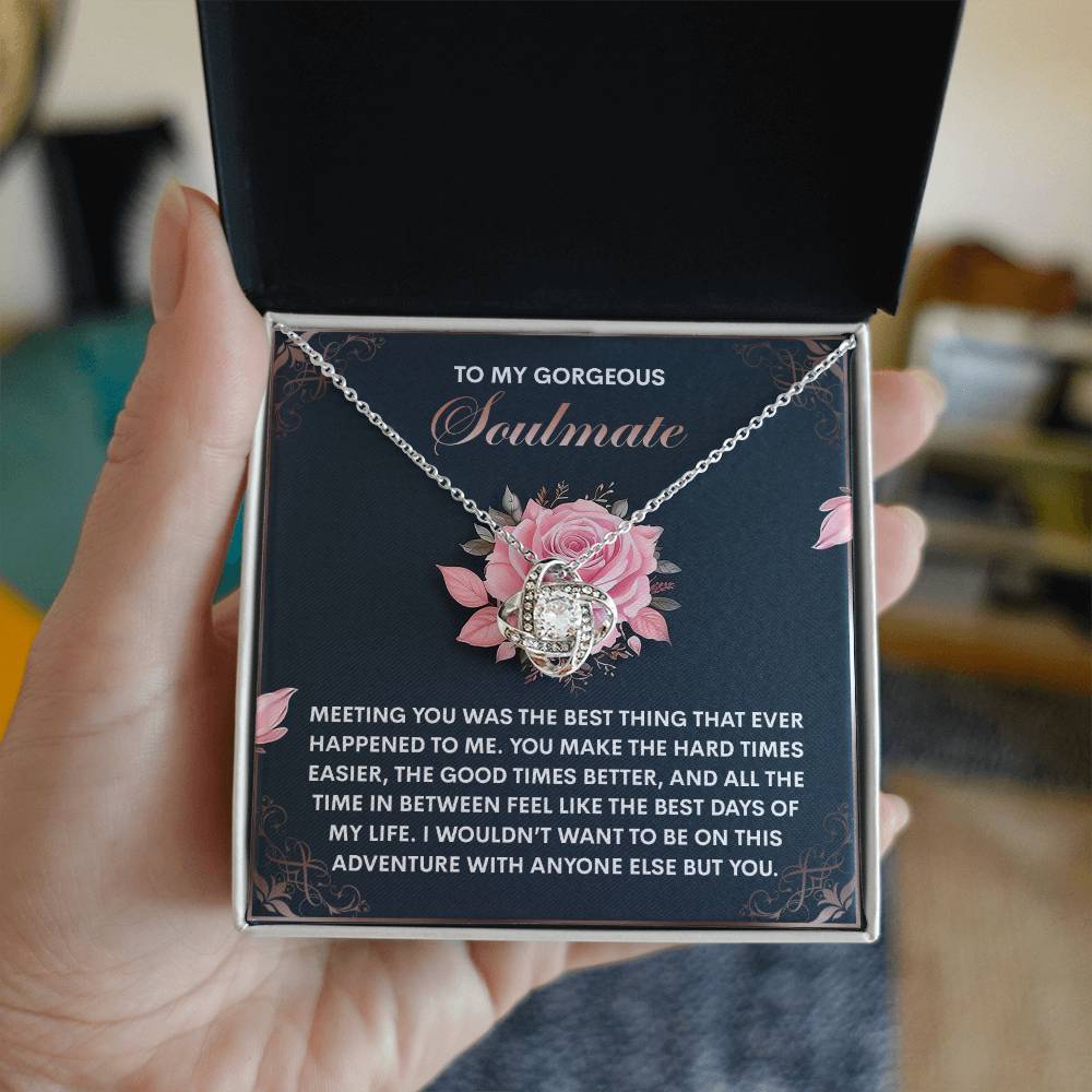 A hand reveals an open box containing the Soulmate-Best Days - Love Knot Necklace with a circular pendant made of cubic zirconia. The lid says, "To My Gorgeous Soulmate," followed by a heartfelt message. It's the perfect personalized gift to express your eternal love.