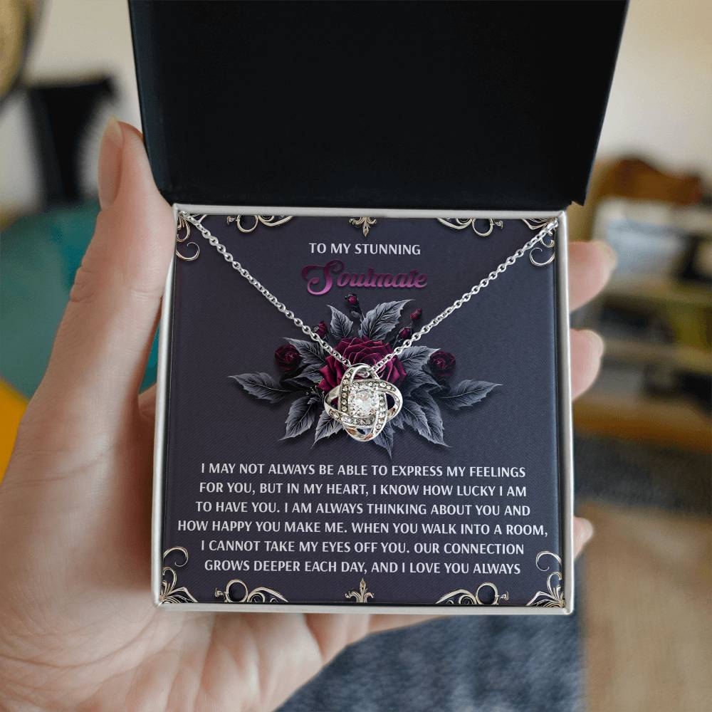 The Soulmate-Eyes Off You - Love Knot Necklace, elegantly finished in white gold and adorned with cubic zirconia, comes in a gift box with a heartfelt message for your significant other and a background of decorative leaves and roses, making it an unforgettable present.