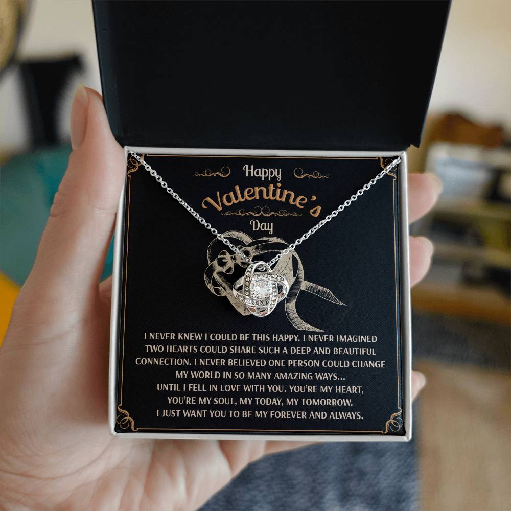 A hand holds an open box featuring the Soulmate-Amazing Ways Love Knot Necklace with a heart pendant. The lid reads "Happy Valentine's Day" and includes a romantic message, making it an ideal personalized gift.