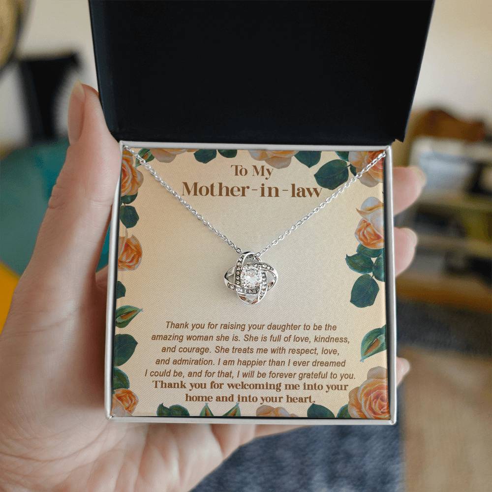 Person holding a jewelry box with the "To Mother-in-law, Grateful To You - Love Knot Necklace" adorned with sparkling cubic zirconia crystals and a heartfelt message addressed to their mother-in-law on the inside cover.