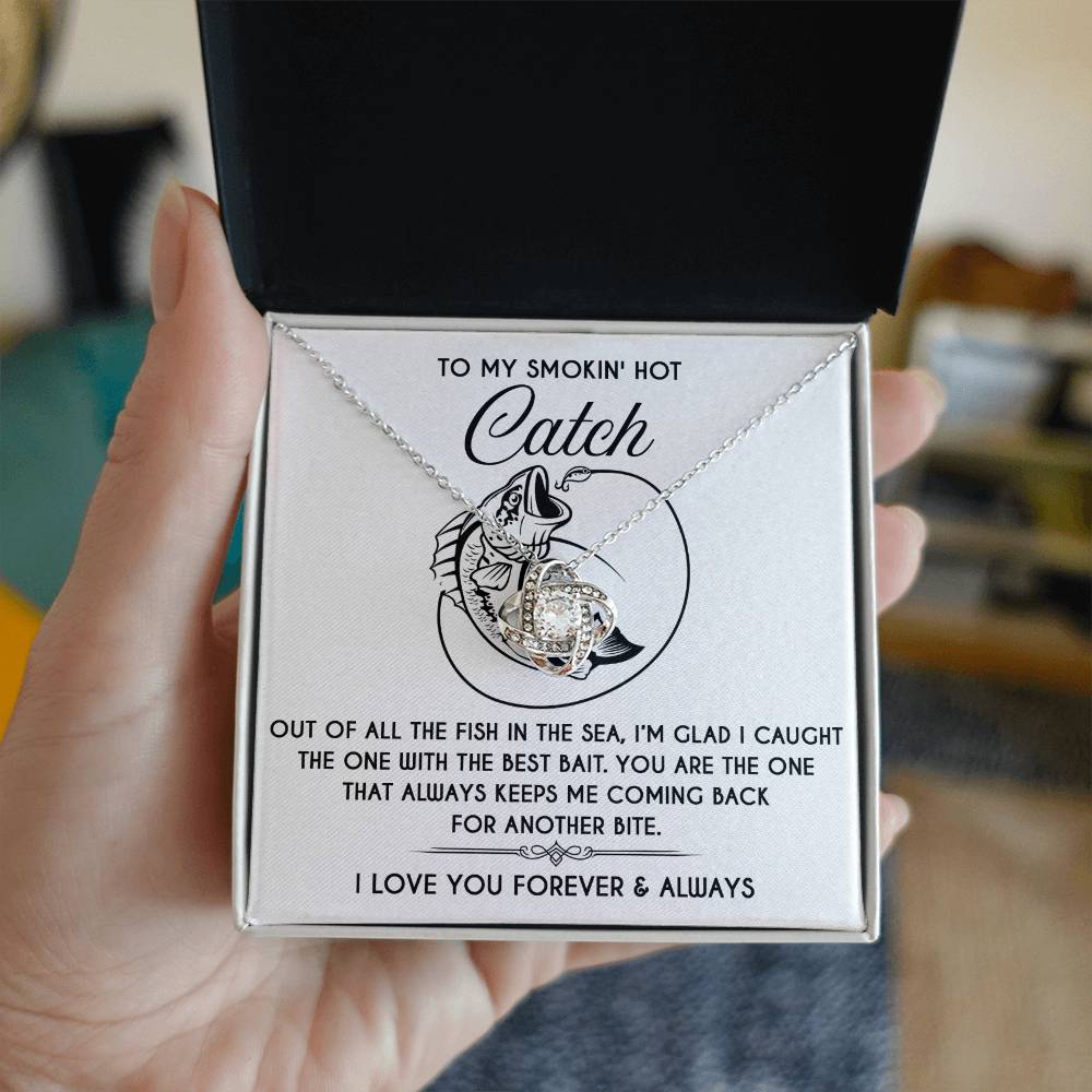 A hand holds a necklace box featuring the "Soulmate-Another Bite - Love Knot Necklace" with a gold finish and Cubic Zirconia. A printed message conveys affection, appreciation, and a fish illustration accompanies the personal note for someone special.