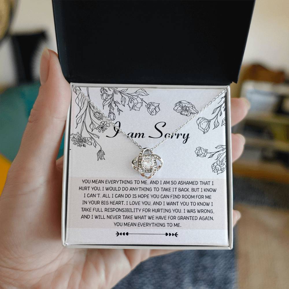 Introducing the "Sorry-Your Big Heart - Love Knot Necklace": This exquisite white gold necklace showcases an elegant intertwined heart design, adorned with shimmering cubic zirconia crystals. It comes complete with a heartfelt card that reads, "I am Sorry," followed by an apologetic message. The entire set is beautifully presented in a floral-printed box.