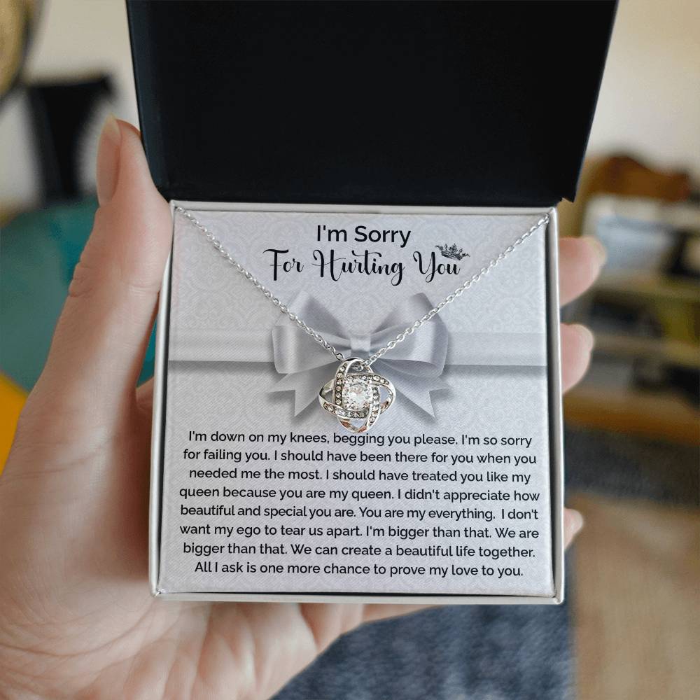 The "Sorry-My Queen - Love Knot Necklace" features a knot-shaped pendant adorned with cubic zirconia crystals and comes in a gift box that includes an apology message, expressing regret and asking for forgiveness and another chance to prove love.