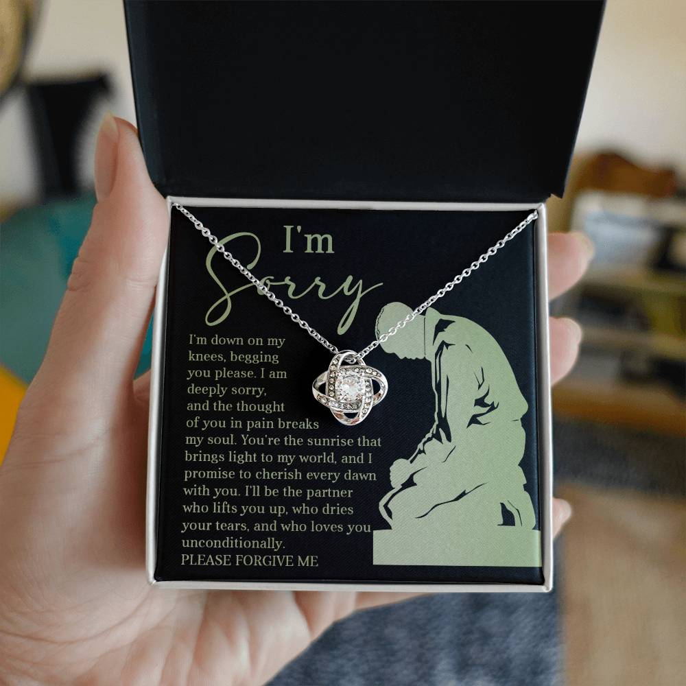 Box containing the "Sorry-On My Knees - Love Knot Necklace," adorned with cubic zirconia crystals and featuring a heartfelt message that reads, "I'm sorry. I'm down on my knees, begging you please. I am deeply sorry. Please forgive me.