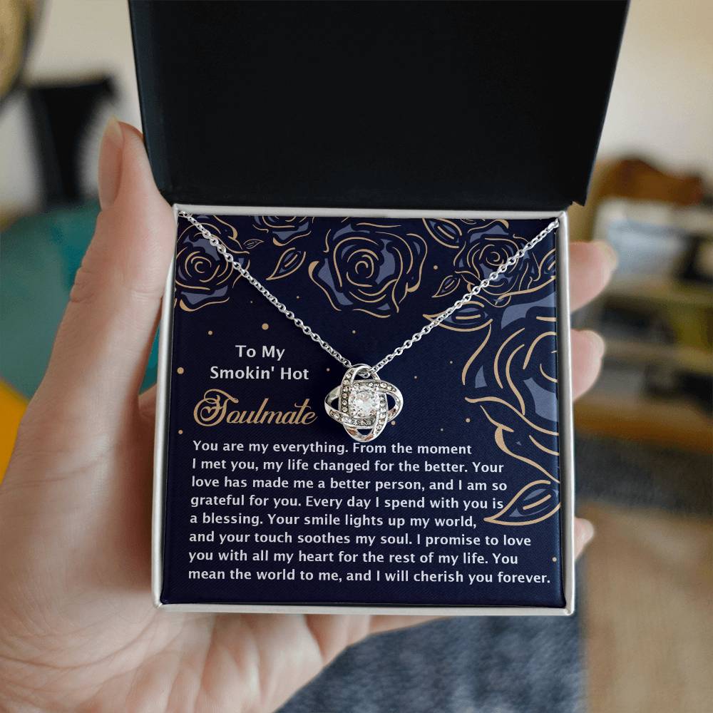 A person holds an open jewelry box with a Soulmate-My Soul 2 - Love Knot Necklace, featuring shimmering cubic zirconia crystals and a romantic message card inside.