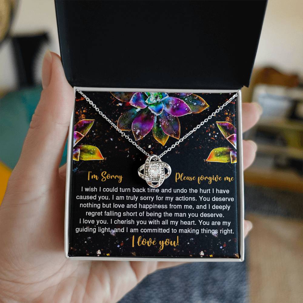 The Sorry-All My Heart - Love Knot Necklace features an interlocking heart pendant on a card with vibrant succulent graphics and the message: "I'm Sorry, Please forgive me. I love you." Adorned with sparkling cubic zirconia crystals, this necklace is available in a choice of white gold or yellow gold finish.