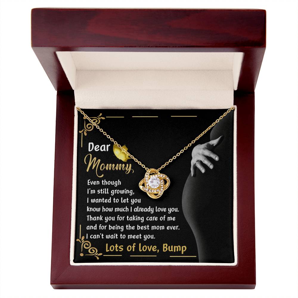 The "To Mama To Be, Best Mom Ever - Love Knot Necklace" features a captivating circular pendant, embellished with radiant cubic zirconia crystals, and is elegantly showcased in a wooden box. The included message card, addressed to "Mommy" from "Bump," conveys heartfelt love and the excitement of their impending meeting. Select either a white gold or yellow gold finish to complete this perfect gift.