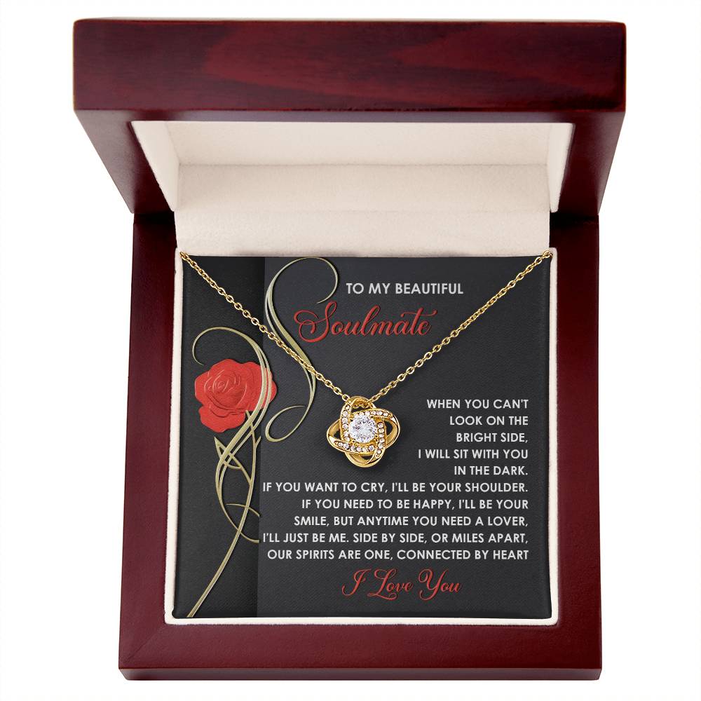 The Soulmate-Be Me - Love Knot Necklace, adorned with a central gemstone and sparkling cubic zirconia crystals, is elegantly presented in a red jewelry box with an inscription inside that tenderly expresses love and support for a soulmate.