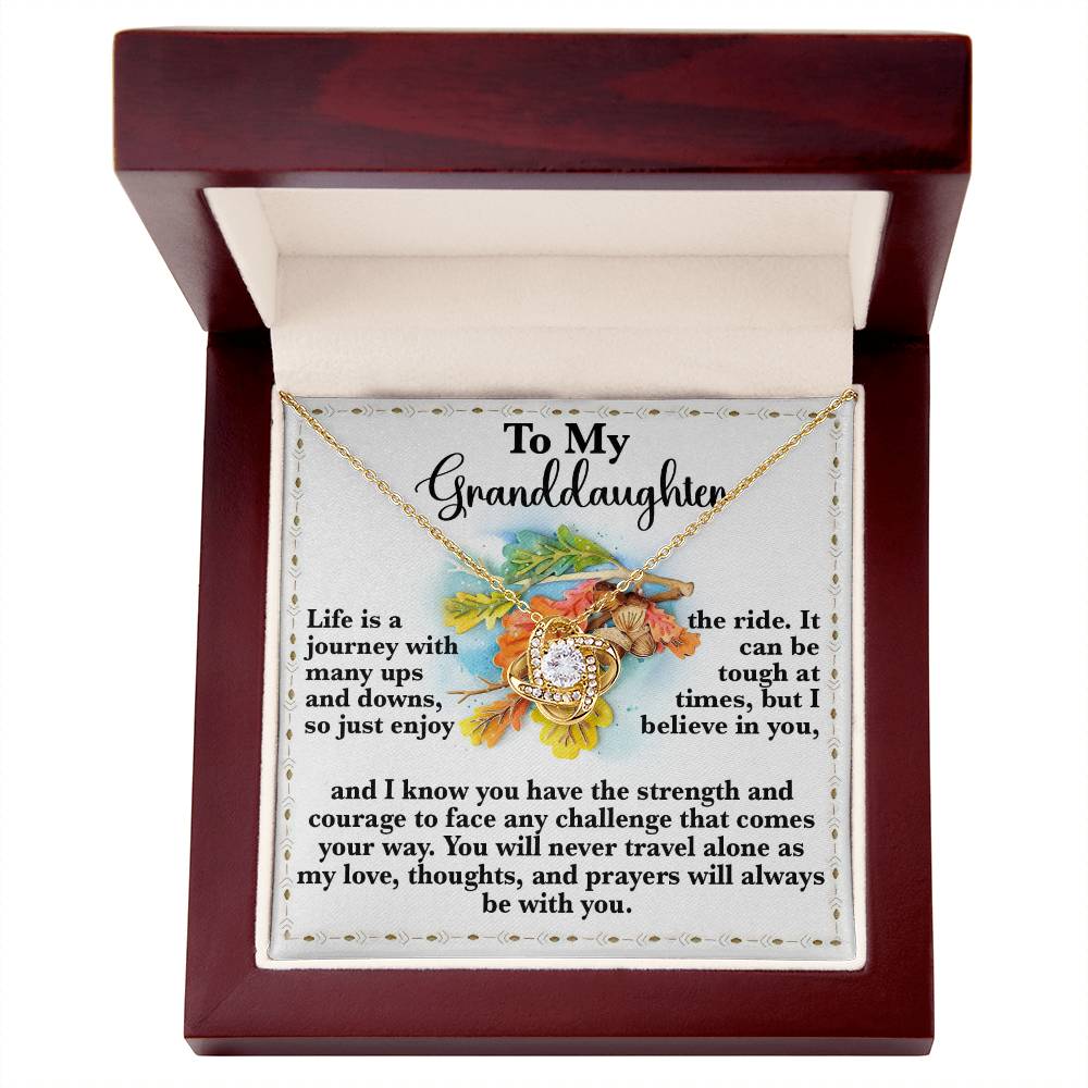 The Granddaughter-Never Travel Alone Love Knot Necklace with a gold finish sparkles with cubic zirconia crystals and is beautifully presented in a jewelry box featuring a heartfelt message for a granddaughter.