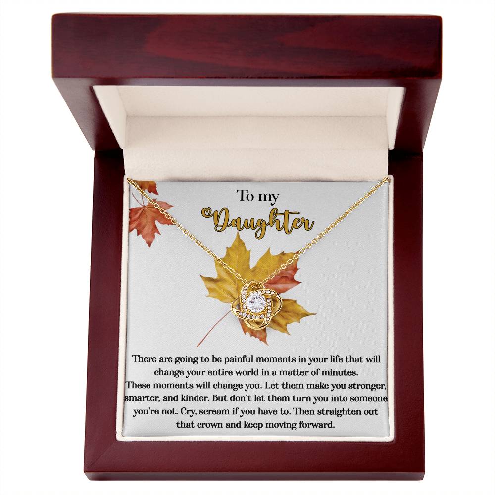 The Daughter-Make You Stronger - Love Knot Necklace, meticulously crafted from 14k white gold and beautifully adorned with cubic zirconia crystals, is nestled inside a wooden box bearing a heartfelt message addressed to a daughter, with autumn leaves adding an extra touch of decoration.