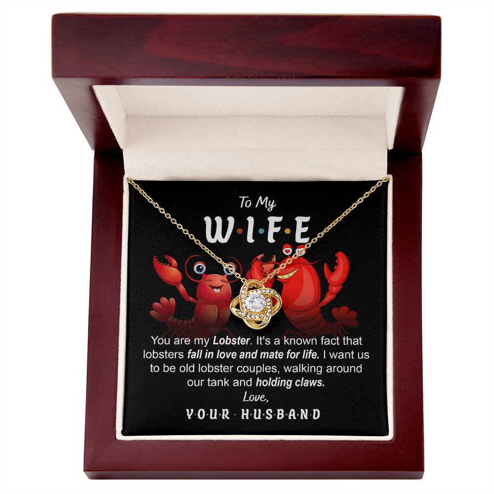 To Wife, Old Lobster Couples - Love Knot Necklace with a heart pendant displayed on a card featuring two cartoon lobsters and a message to a wife, discussing lifelong lobster mates and expressing love from a husband. The necklace sparkles with cubic zirconia crystals, symbolizing the unbreakable bond of your love.