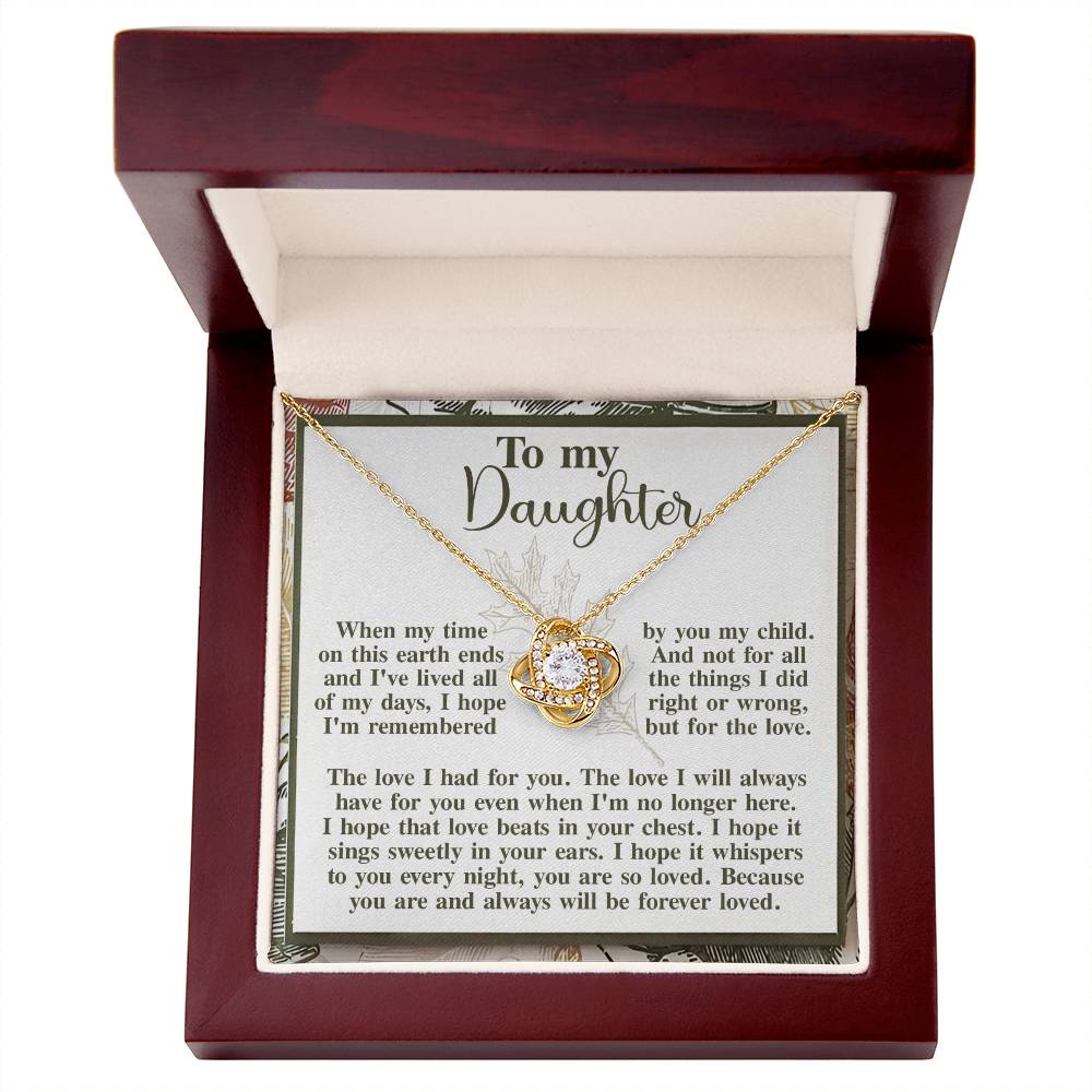An open jewelry box showcases the "Daughter-In Your Ears - Love Knot Necklace" embellished with cubic zirconia crystals, accompanied by a message card addressed "To my Daughter," containing a heartfelt note about parental love and remembrance.