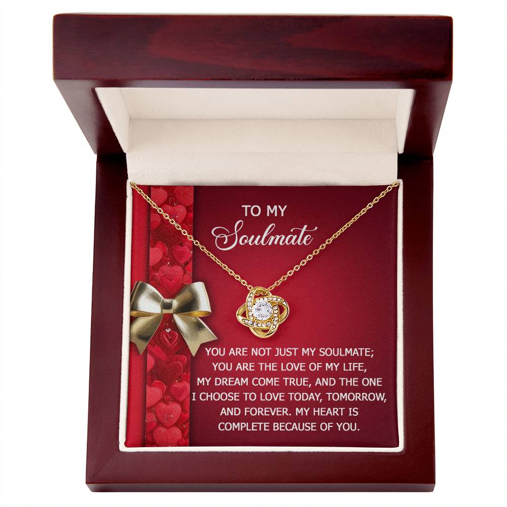 The Soulmate-Because Of You Love Knot Necklace features a circular pendant adorned with sparkling cubic zirconia crystals, presented in a jewelry box. The heartfelt message "To My Soulmate" is elegantly displayed against a heart-patterned background, symbolizing an unbreakable bond.