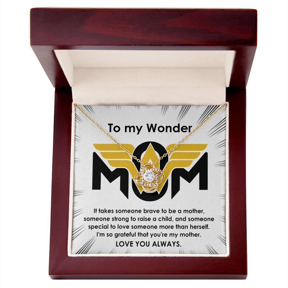 The "To Mom, More Than Herself - Love Knot Necklace" is presented in an open box, featuring a sparkling pendant adorned with cubic zirconia crystals and a lustrous gold finish. It comes with a heartfelt message addressed to "My Wonder MOM," expressing gratitude and appreciation for a mother's strength and love.