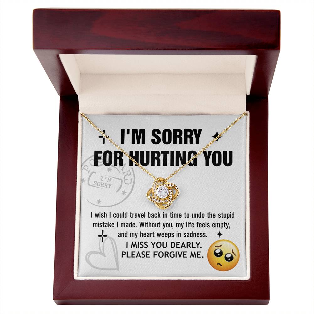 The Sorry-Travel Back - Love Knot Necklace, featuring a heart-shaped pendant adorned with cubic zirconia crystals, is displayed in an open wooden box alongside an apology message to express regret for any hurt caused.