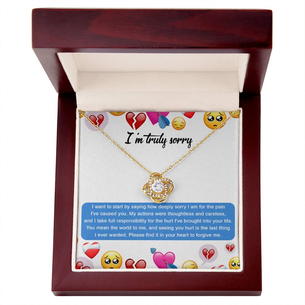 The Sorry-How Deeply Sorry - Love Knot Necklace features a pendant with an intertwined design, adorned with sparkling cubic zirconia crystals. The piece rests on a card that includes an apology message accompanied by various emoticons, such as hearts and sad faces.